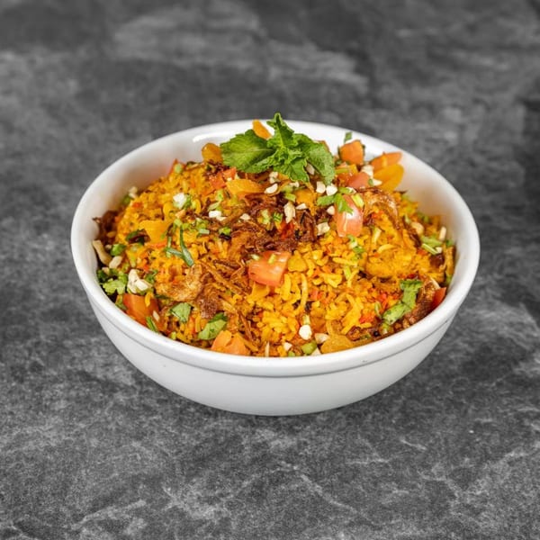 A white bowl filled with vibrant Indian biryani, garnished with mint, fried onions, and chopped vegetables.